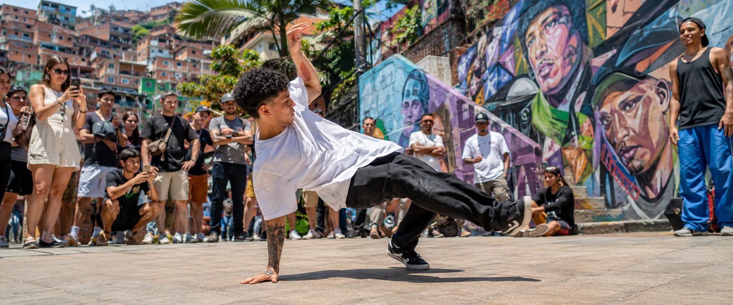 Breakdancer performing in Comuna 13 plaza with crowd watching