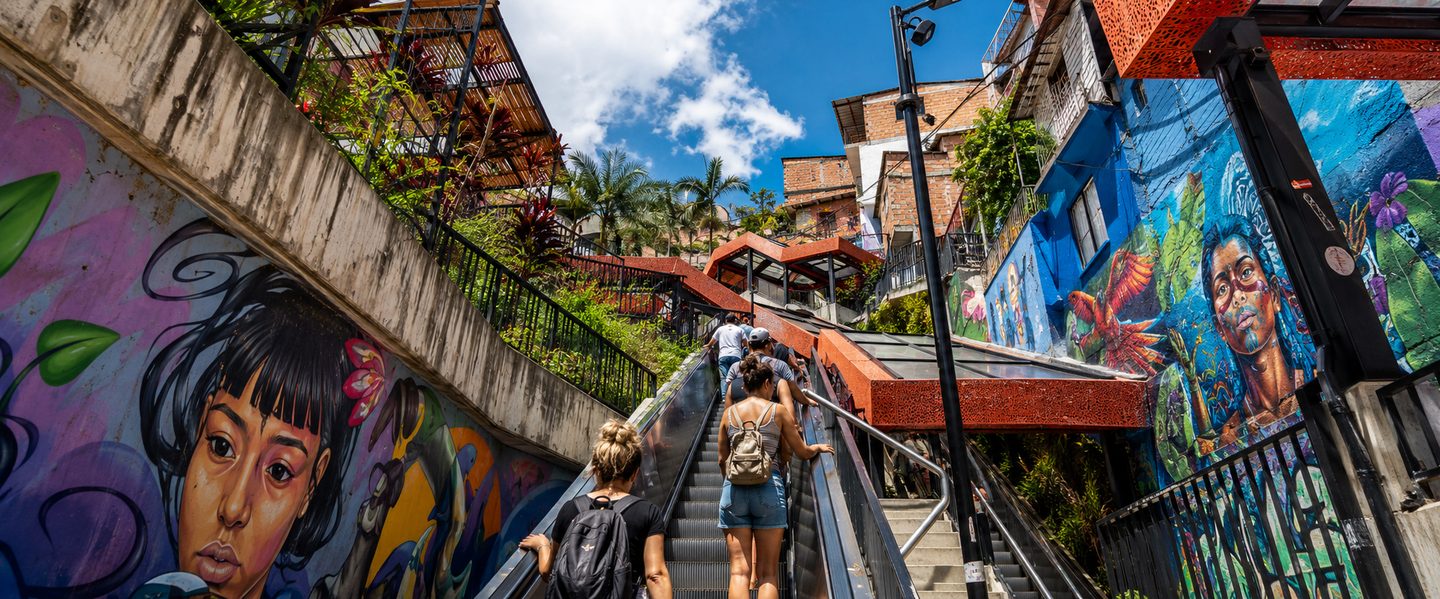 Tourists casually walking up Comuna 13 escalators on a sunny day